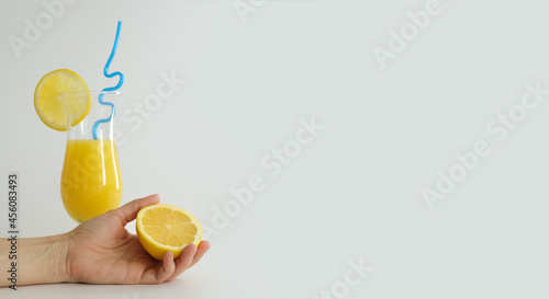 Fresh orange juice in glass, decorated with slice of lemon and blue straw. Summer cocktail on the white background. Colorful template. Free space for text, copy space. photo