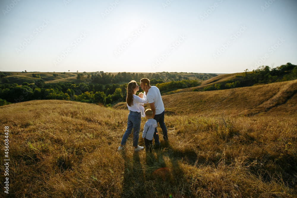 family with small children posing in nature against the background of the evening sun