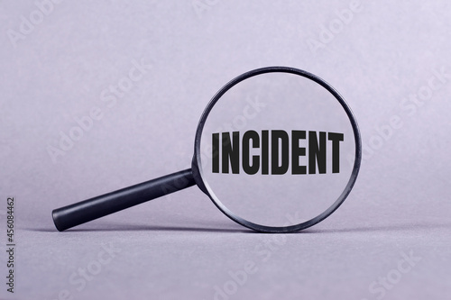 Slika na platnu Magnifying glass with INCIDENT lettering on a gray background.