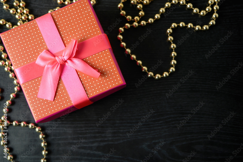 Closeup of red present box with pink ribbon and bow on the black wood Closeup of red present box with pink ribbon and bow on the black wood