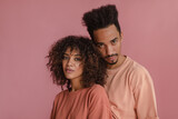 close-up of couple of mulattoes expressively look into camera lens indoors. young brunette with meek afro hair stands with her backside to handsome tall man with high hairstyle.