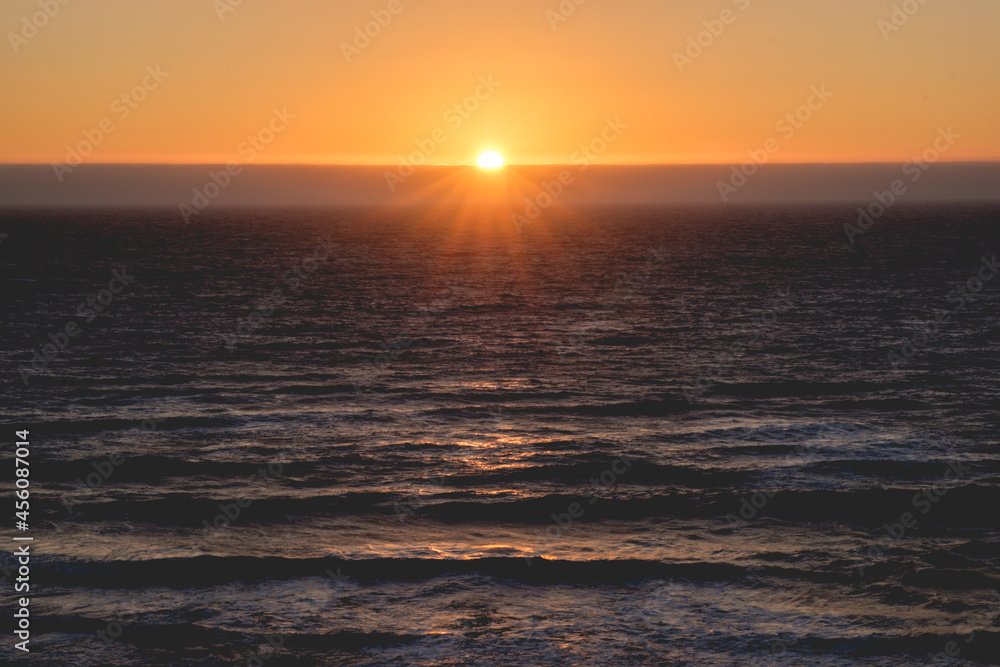 Obraz premium Panoramic view of the pacific ocean and beautiful sunset in the horizon with sun and rays in the center 