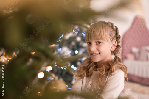 Little girl spends time decorating the Christmas tree. Preparing for the holidays. Santa will be glad