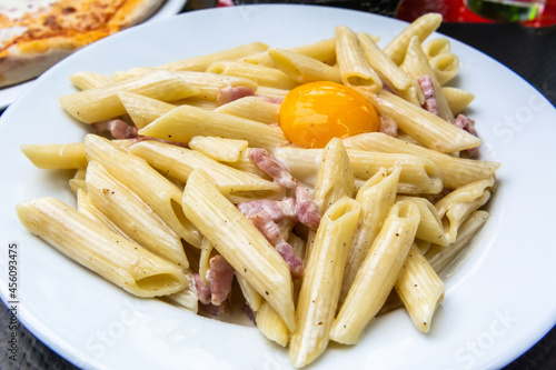 Принти на полотні Pasta penne ala carbonara with egg yolk and ham