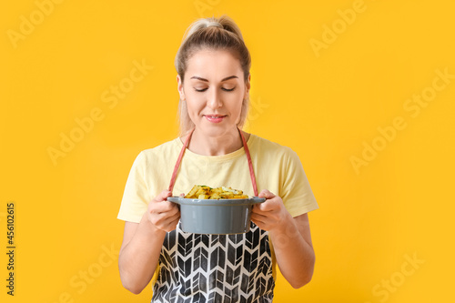 Young housewife with tasty potato dish in saucepot on color background photo