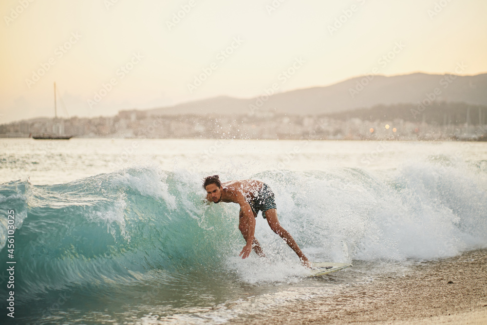 Man on a skimboard catching a wave in a beach in Palma de Mallorca, Spain