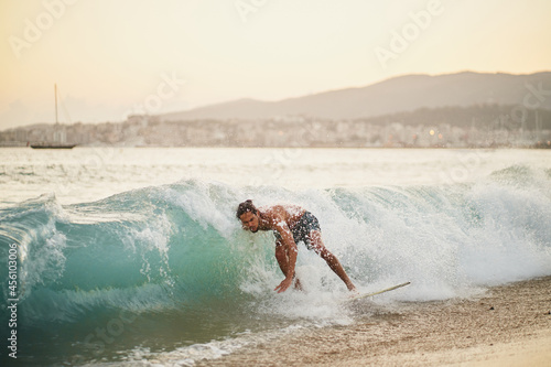 Man on a skimboard catching a wave in a beach in Palma de Mallorca  Spain