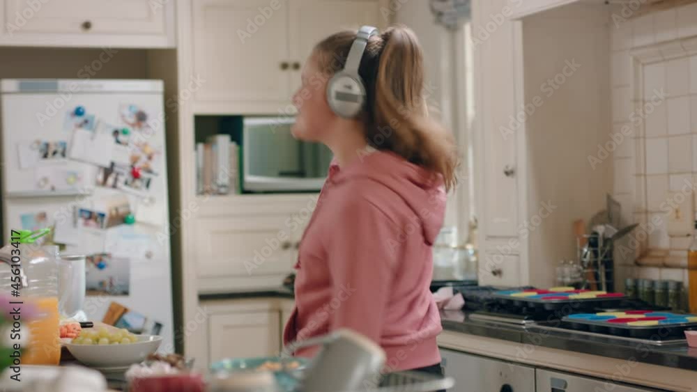 happy teenage girl dancing in kitchen having fun celebrating weekend performing funny dance moves listening to music wearing headphones happy teenage girl dancing in kitchen having fun celebrating weekend performing funny dance moves listening to music wearing headphones