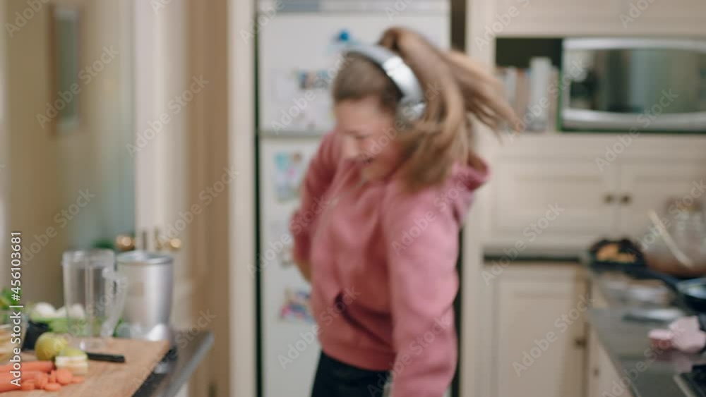 happy teenage girl dancing in kitchen having fun celebrating weekend performing funny dance moves listening to music wearing headphones