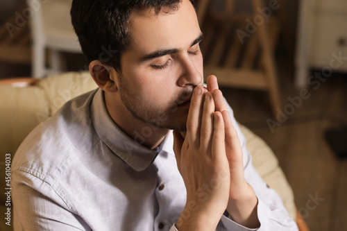 Young man praying at home in evening