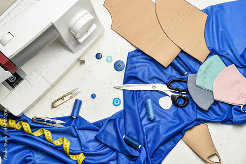 Sewing machine with tailor's supplies and protective masks on light background