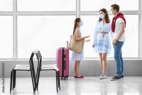 Family in medical masks waiting for their flight at the airport