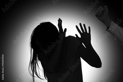 Silhouette of woman mistreated by man on dark background photo