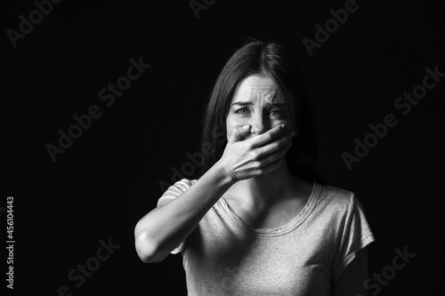 Scared young woman on dark ...
