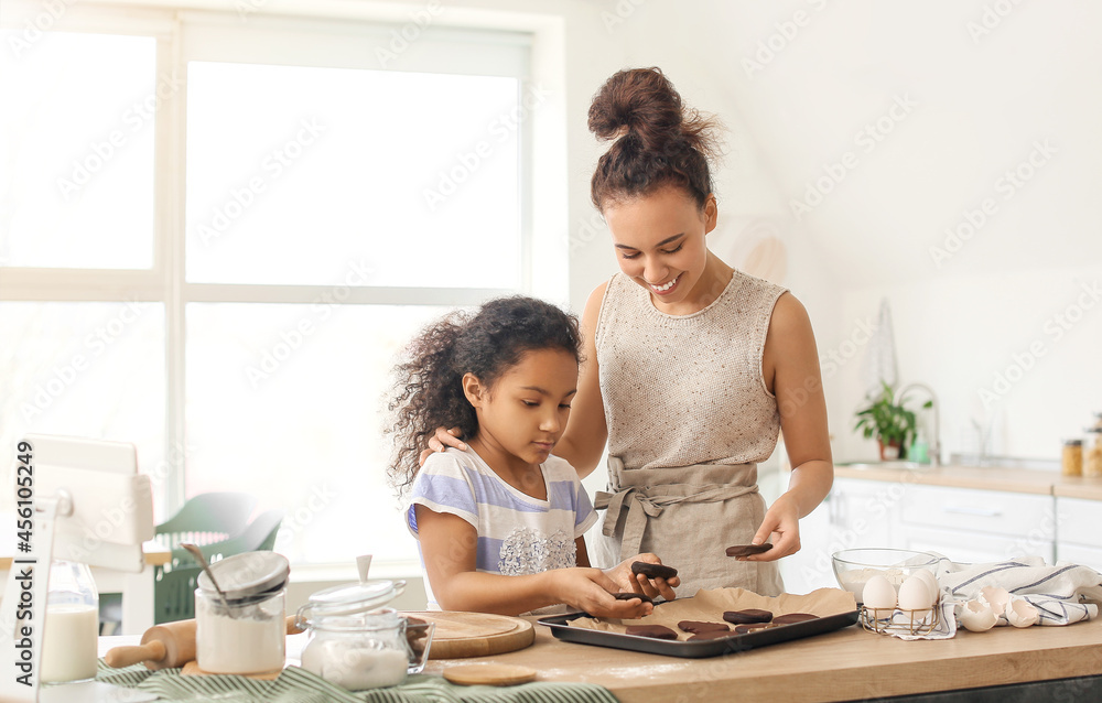 African-American little girl and her mother preparing cookies in kitchen African-American little girl and her mother preparing cookies in kitchen