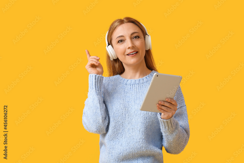 Mature woman with tablet computer pointing at something on color background Mature woman with tablet computer pointing at something on color background