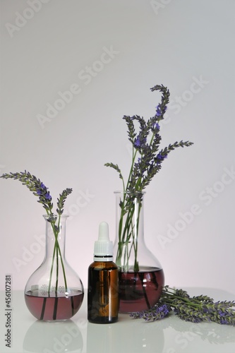Lavender Essential oil.Glass bottle   laboratory flasks with lavender flowers on a light purple background.Organic natural cosmetics with lavender extract. 