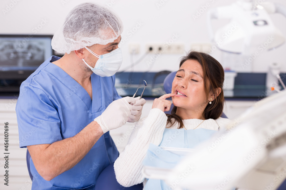 Unhappy hispanic patient woman having a toothache in dental chair at