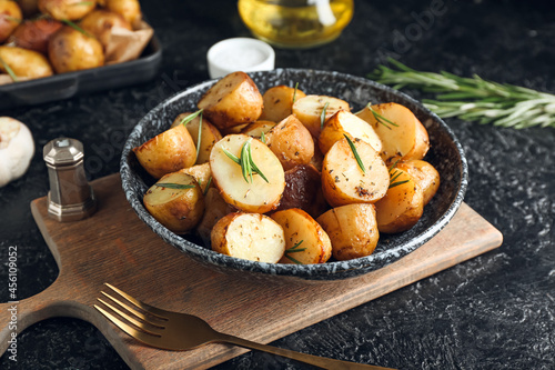 Plate with baked potatoes and rosemary on dark background