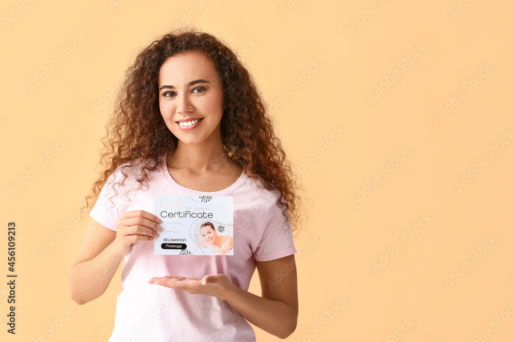 Young African-American woman with gift certificate for massage on color background Young African-American woman with gift certificate for massage on color background