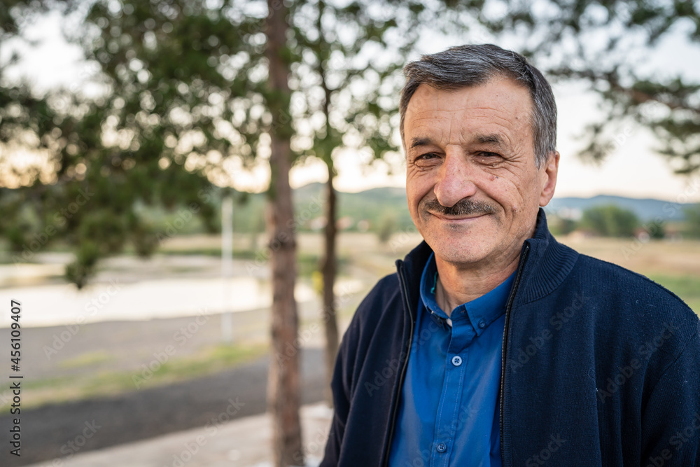 Portrait of senior caucasian man in nature standing in spring or autumn day - close up of cheerful male standing looking to the camera - real people concept Portrait of senior caucasian man in nature standing in spring or autumn day - close up of cheerful male standing looking to the camera - real people concept