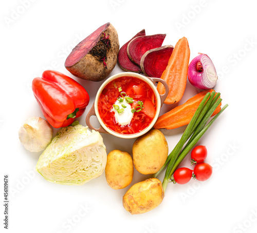 Pot of tasty borscht and ingredients on white background