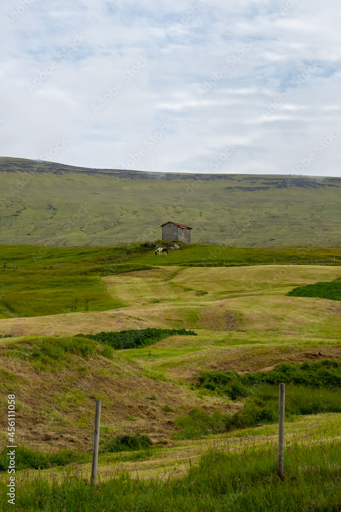 Obraz premium Beautiful aerial view of a traditional lonely house -barn in the middle of the mountains in the Faroe Islands