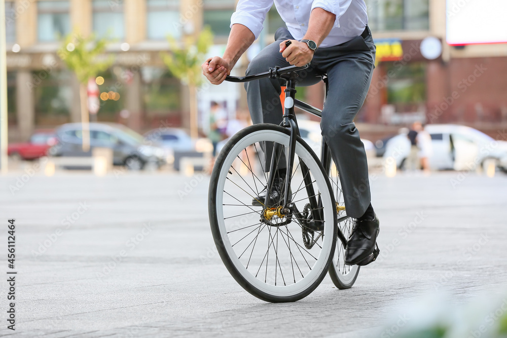 Fototapeta premium Businessman going to work by bicycle on city street