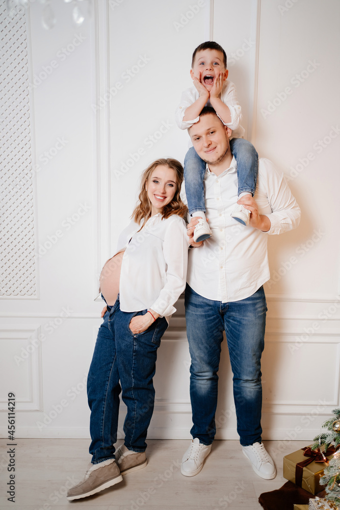 happy family. pregnant mother with her son and father in jeans and a white shirt happy family. pregnant mother with her son and father in jeans and a white shirt