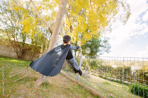 Little kid dressed up as Batman on a swing photo