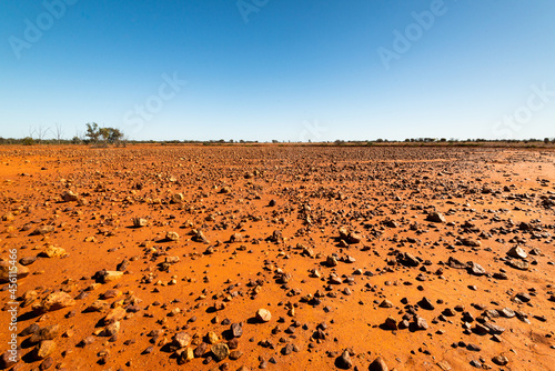 Low view of stony desert country with gibbers, orange soil and clear blue sky photo