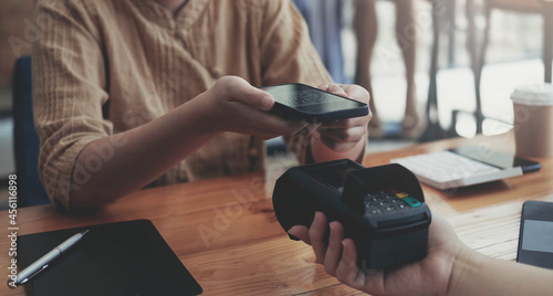 A woan using her mobile to made a payment wireless with EDC machine or credit card terminal. Mobile payment concept with virtual credit card photo