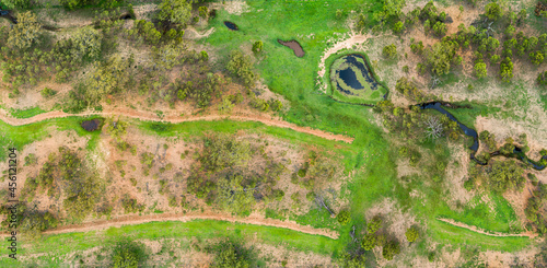 Erosion prevention embankments and creek flowing to dam in paddock with new green growth photo