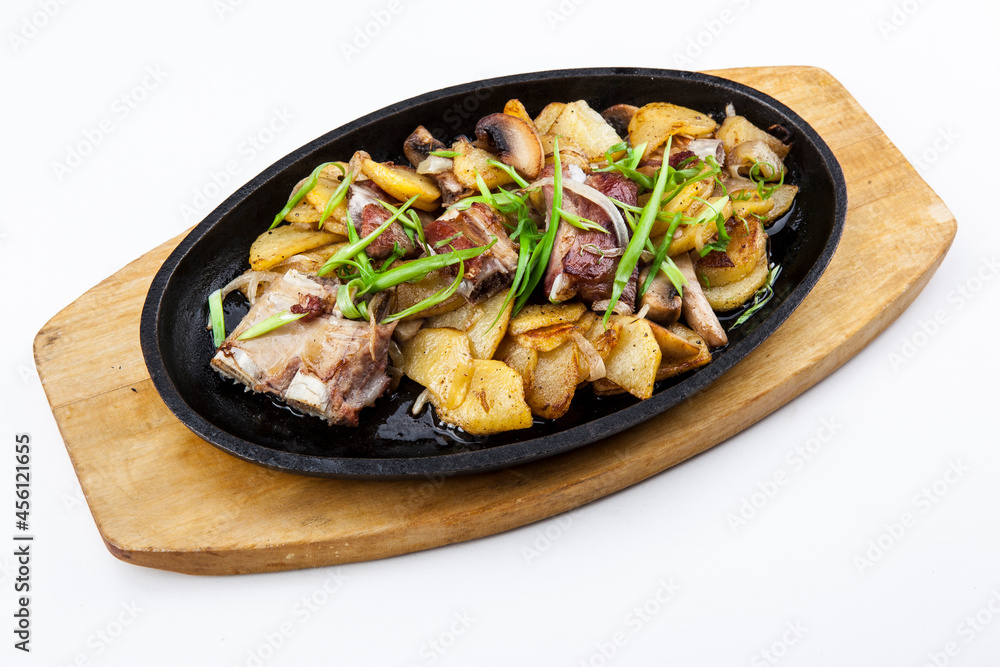 pork ribs with fried potatoes, mushrooms and green onions in a pan