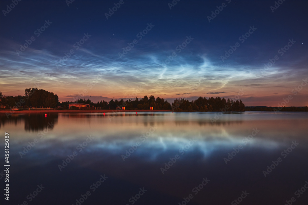 Reflection of noctilucent clouds in the lake water at summer night.