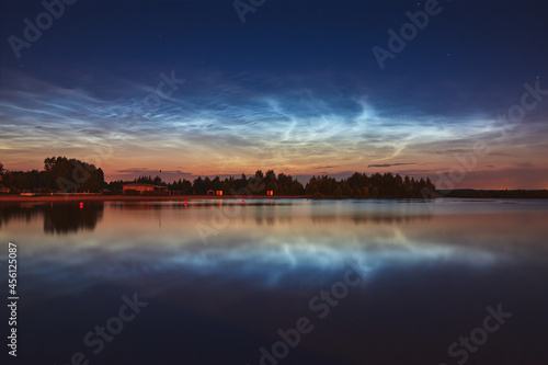 Reflection of noctilucent clouds in the lake water at summer night.