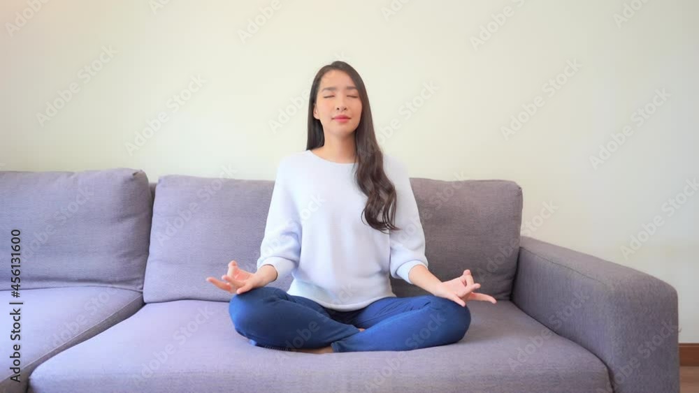 Beautiful Woman Sitting Cross-Legged on Couch Practicing Yoga at Home. Beautiful Woman Sitting Cross-Legged on Couch Practicing Yoga at Home.