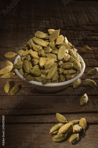 Green cardamom seeds against wooden background