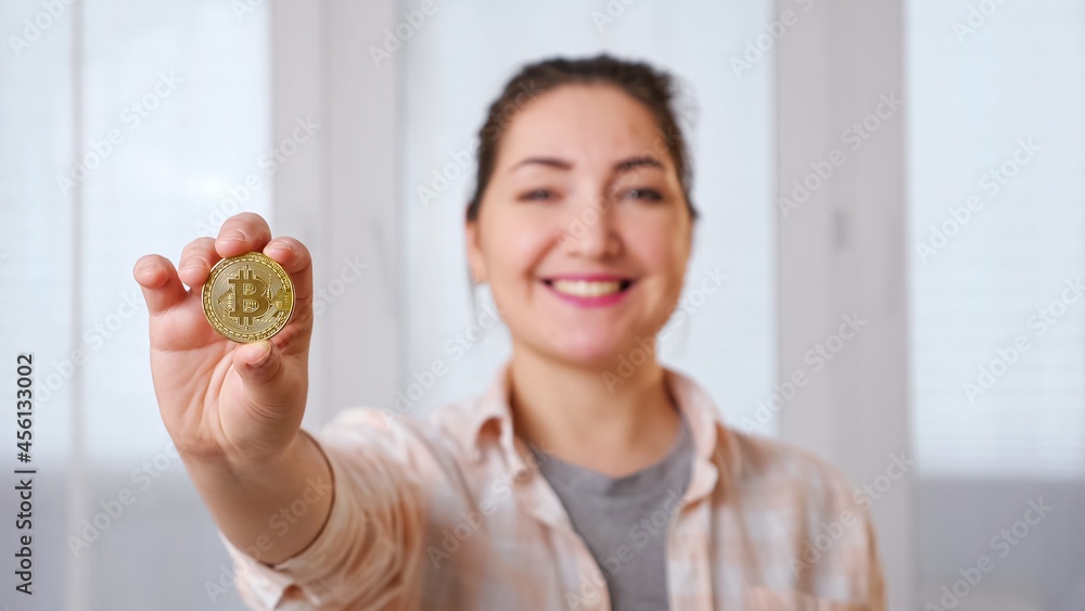 Blurred young brunette woman holding golden bitcoin in her hand, selective focus Blurred young brunette woman holding golden bitcoin in her hand, selective focus