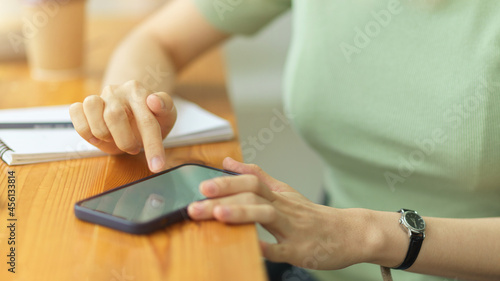 Close up, young woman using smartphone, touching mobile screen, surfing internet