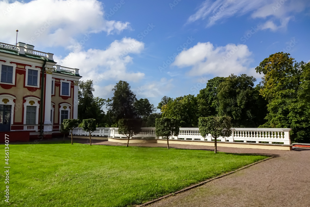 Landscape in Kadriorg park. Green trees on the back. Red and white barocco building facade on the left. Summer sunny day. Green grass. Tallinn, Estonia, Europe. August 2021