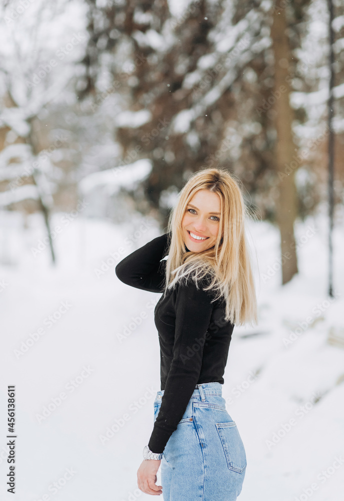 Stylish blonde in baggy jeans posing in a winter park. Stylish blonde in baggy jeans posing in a winter park.