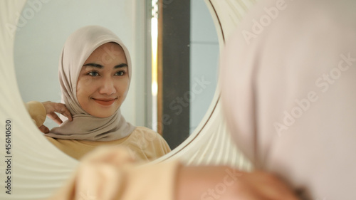 the beautiful young Muslim smiles sweetly in the mirror