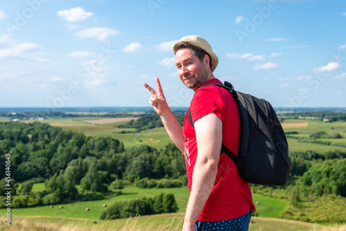 Man backpacker smiling and showing victory sign.Male outdoors smiling and showing victory sign at summer day.