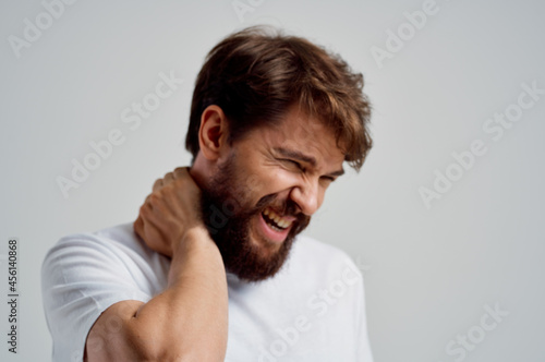emotional man in a white t-shirt stress medicine pain in the neck light background