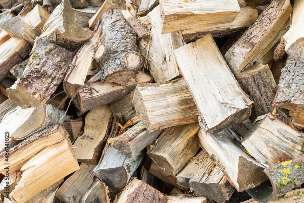 Fuel and heat source for the winter season.Preparing for the firewood heating season. Chopped firewood of different trees,outdoors. Fuel and heat source for the winter season.Preparing for the firewood heating season. Chopped firewood of different trees,outdoors.