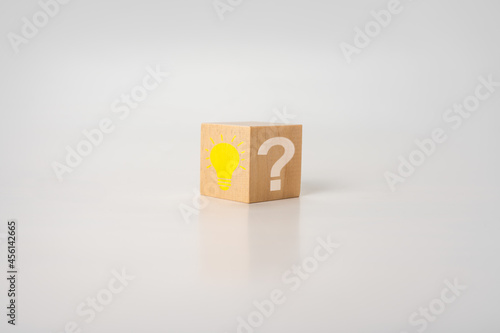 Wooden cube with bright light bulb and question mark on white table. Creative idea, Innovation and Solution concepts. Wooden cube with light bulb icon and question mark symbol. © Celt Studio