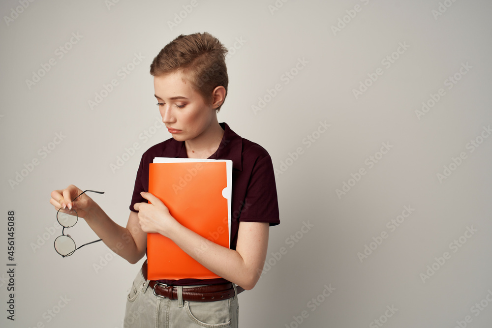 female student with an orange folder in hand light background female student with an orange folder in hand light background