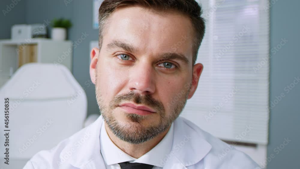 Portrait view of the caucasian male doctor sitting in his cabinet and looking at the camera. Handsome man physician at work in clinic. Healthcare concept Portrait view of the caucasian male doctor sitting in his cabinet and looking at the camera. Handsome man physician at work in clinic. Healthcare concept