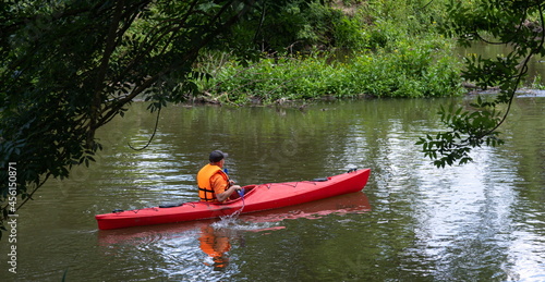 Traveler with paddle and kayak on a small river
